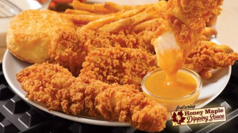 Chicken waffle tenders with fries and honey maple sauce on plate