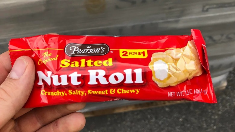 A hand holds a Pearson's Salted Nut Roll in a red wrapper.