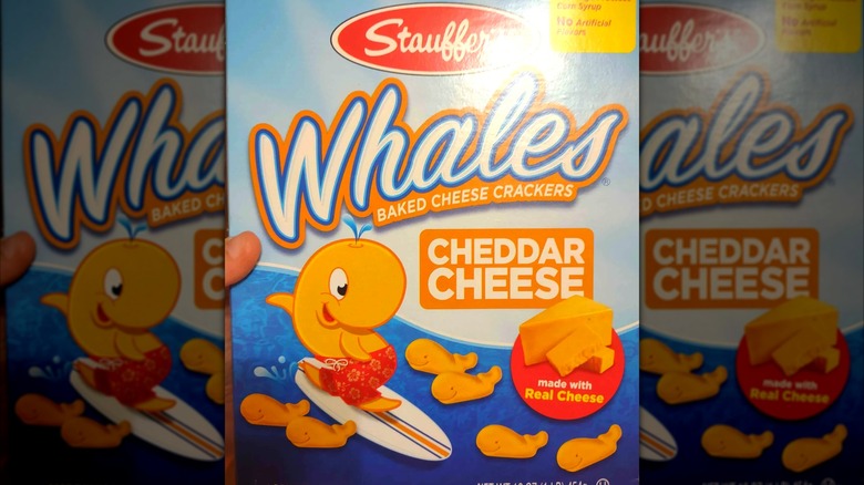 A hand holds a box of Stauffer's Whales Baked Cheese Crackers.