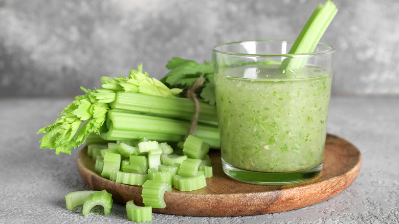 Glass of celery juice with fresh celery in the background