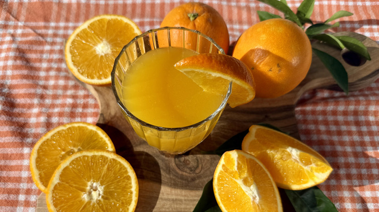 Freshly squeezed orange juice surrounded by oranges