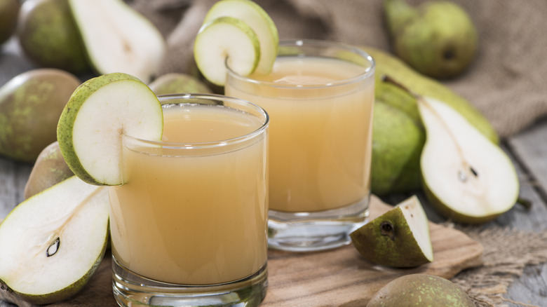 Glass of homemade pear juice surrounded by fresh pears