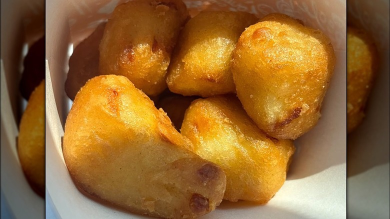 A container of some small, round, golden cheesy bites from Popeyes