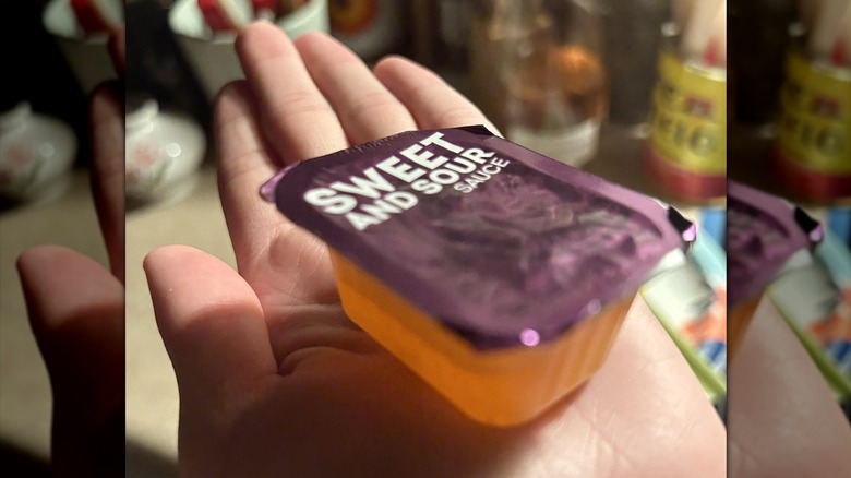 A sealed package of Wendy's sweet and sour sauce held in an outstretched palm