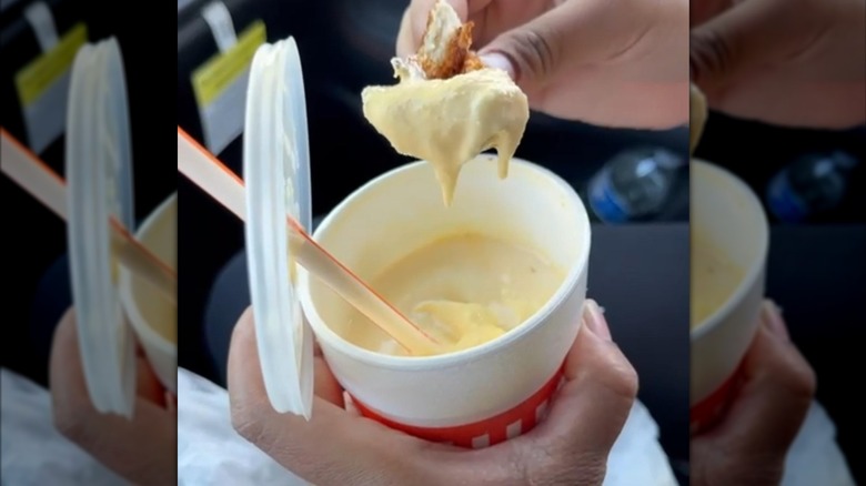 Hands holding a Whataburger banana shake and dipping something into it