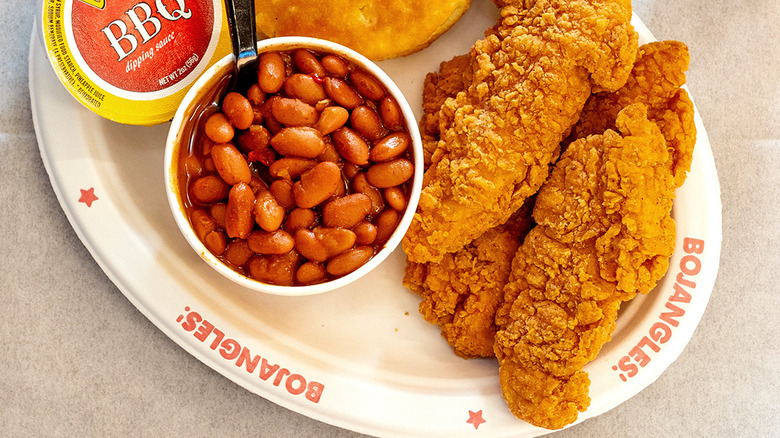 Platter of chicken tenders, biscuit, pintos, and BBQ sauce cup on a paper Bojangles plate