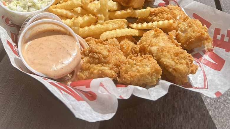 Basket of Raising Cane's chicken fingers, fries, cole slaw, and sauce