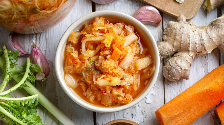Bowl of kimchi surrounded by various aromatics