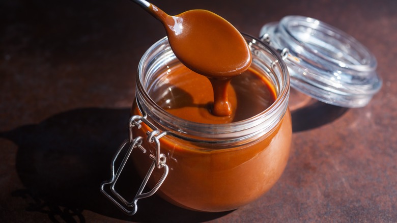 Spooning caramel sauce from opened jar