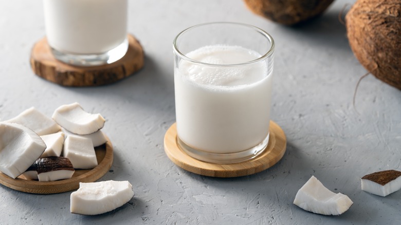 Glasses of coconut milk next to pieces of fresh coconut