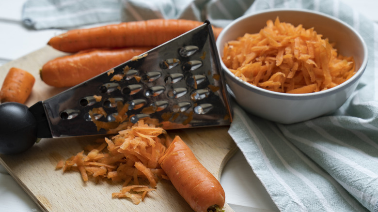 Grating carrots on wooden cutting board