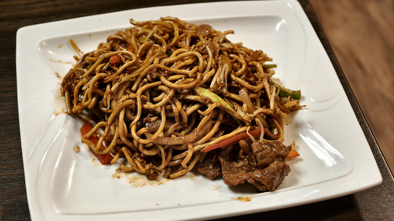 Chinese stir-fried noodles with beef on white plate