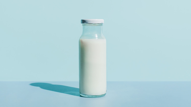 Glass bottle of milk against a light blue background