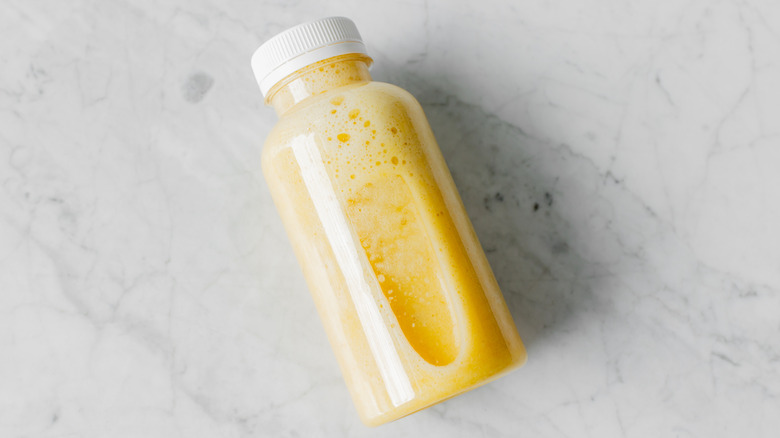 Orange juice in a plastic bottle, lying flat on a marble countertop