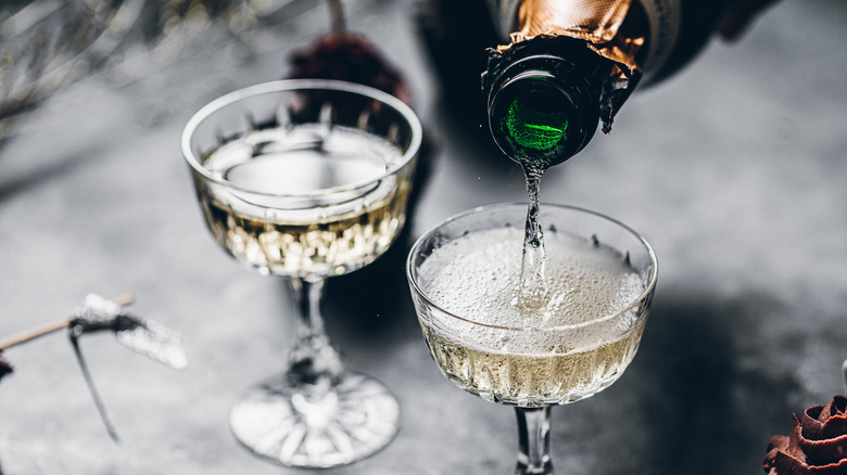 Close-up of pouring champagne in a glasses over black table