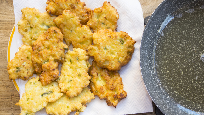 fried corn fritters near a pan with boiling oil