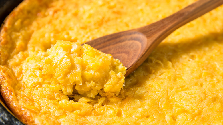 close up of wooden spoon in corn pudding