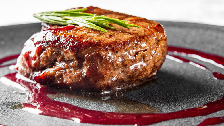 Close up of filet mignon on bed of potatoes with leafy greens on top