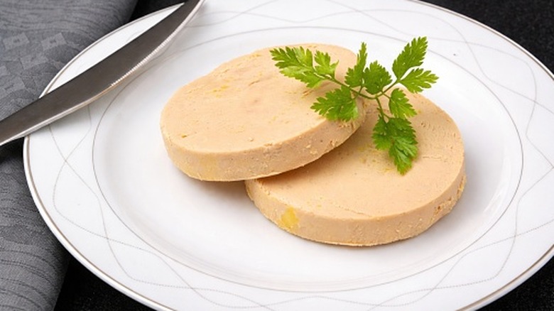Slices of duck foie gras on a white plate with garnish