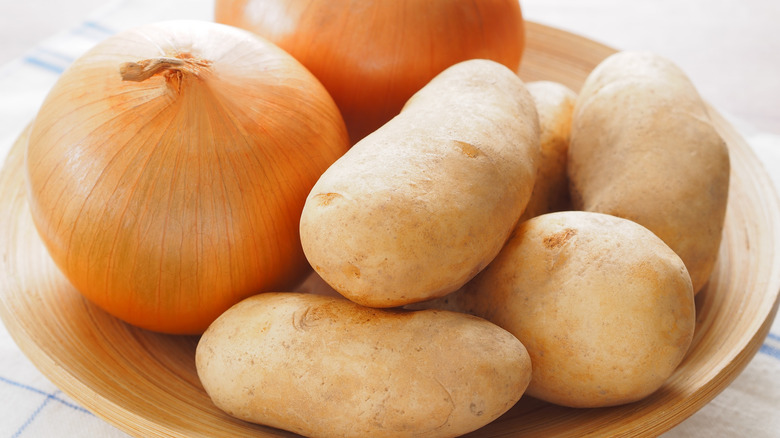 Potatoes and onions stored together in a wooden bowl