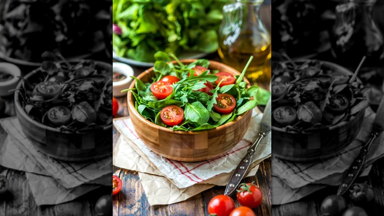 A wooden bowl filled with tomatoes and spinach leaves
