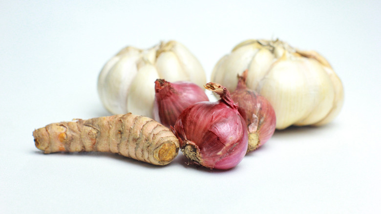 Garlic bulbs, ginger root, and red onions on a white background
