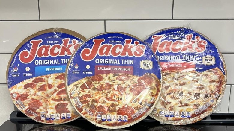 3 Jack's Original Thin Crust pizzas on a stove leaning against the wall