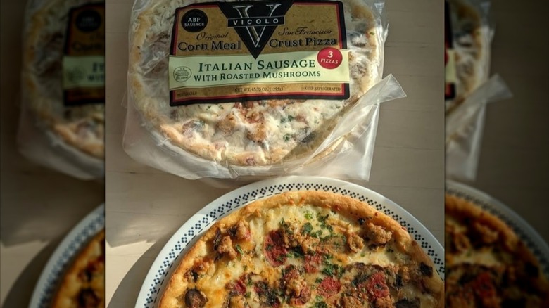 A pizza on a plate next to a package that says Vicolo Original Corn Meal Italian Sausage with Roasted Mushroom