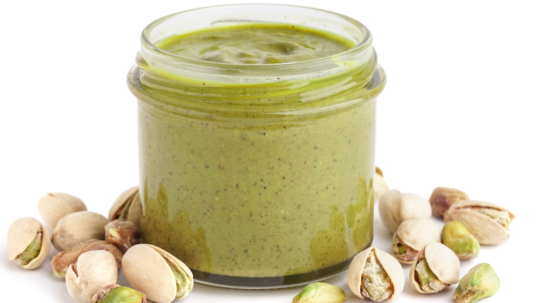 pistachio butter with nuts on white surface
