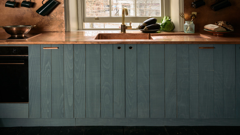 A luxury designer kitchen featuring hand-aged, distressed copper counters and backsplashes