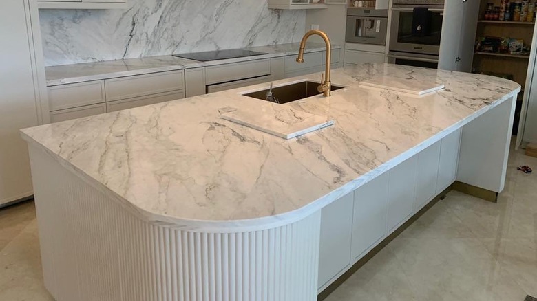 A contemporary kitchen with white dolomite counters, backsplash, and kitchen island