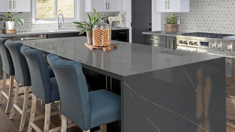 An elegant kitchen with a waterfall island in dark gray marbled soapstone