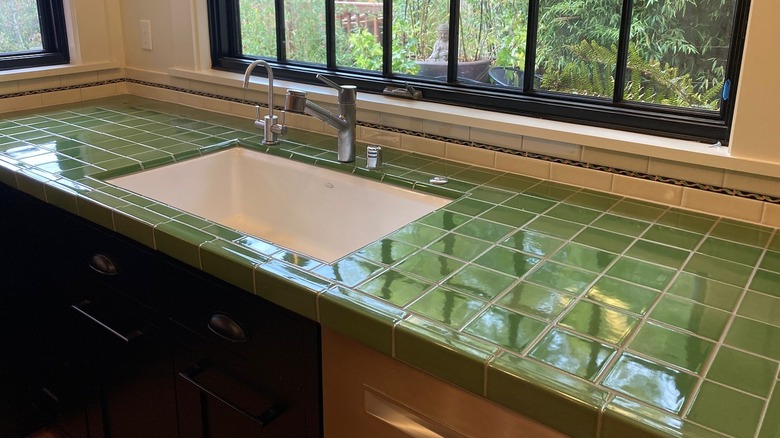 A cheerful, bright kitchen with dark green tile counters