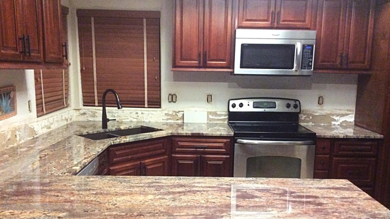 A kitchen with Crema Bordeaux granite countertops and warm cherry wood cabinets
