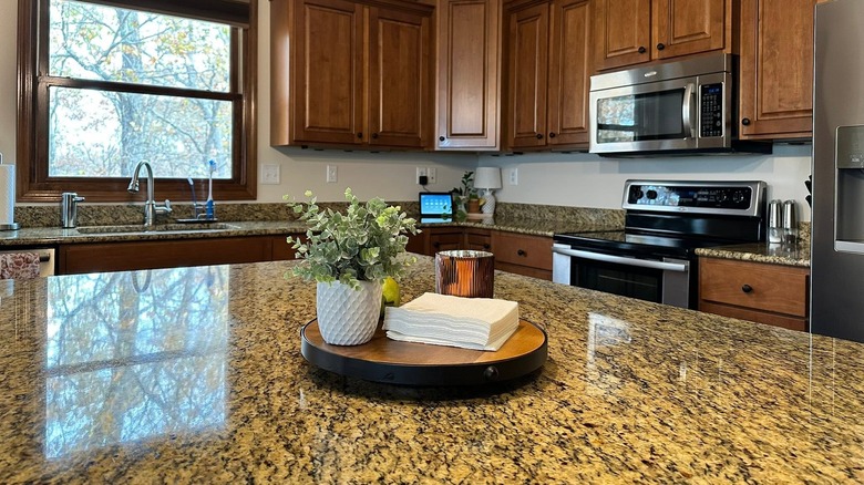 A kitchen island with a Giallo Fiorito granite top and deep golden walnut cabinets