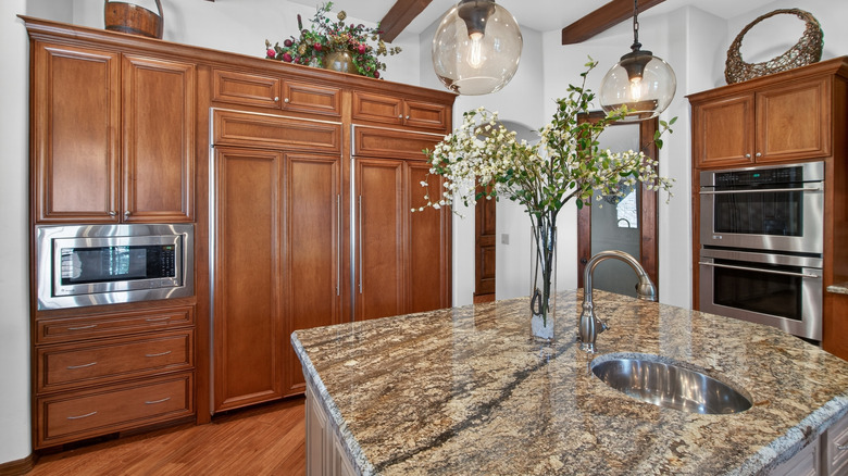 An open kitchen with a granite countertop and warm wood cabinetry and kitchen island