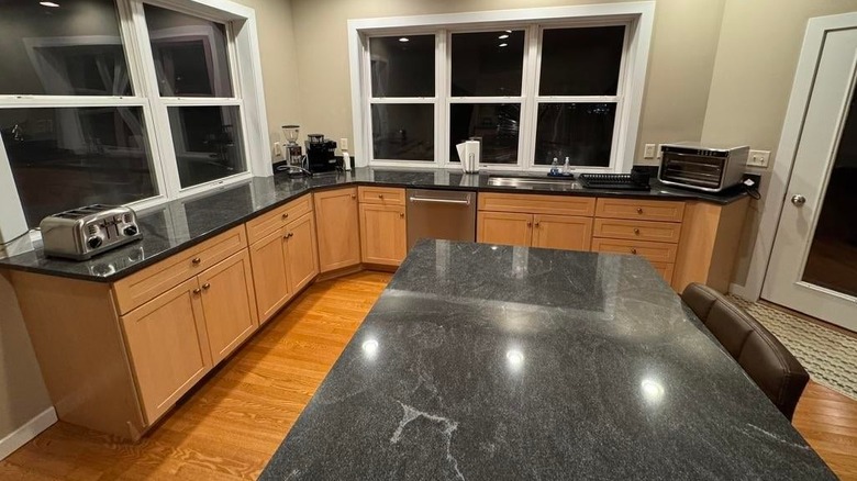Leathered Virginia Mist granite countertops installed in a kitchen with warm honey oak cabinets