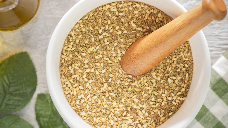 A dukkah blend of seeds, spices and nuts in a bowl with a wooden utensil