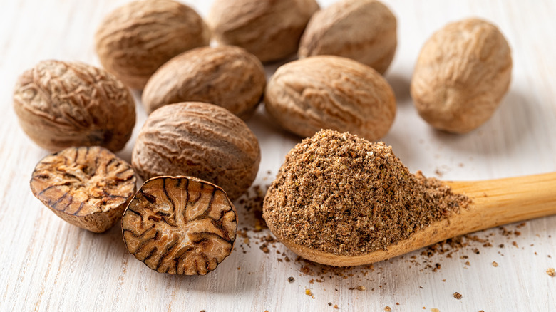 Whole nutmeg pieces with fround nutmeg in a spoon