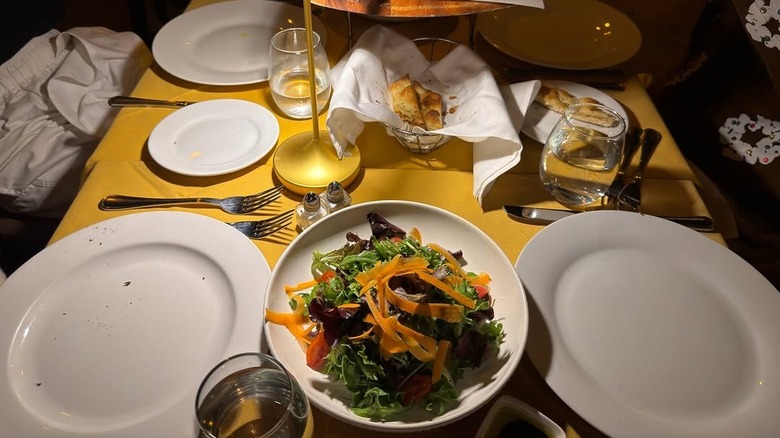 table with empty plates and salad in the center
