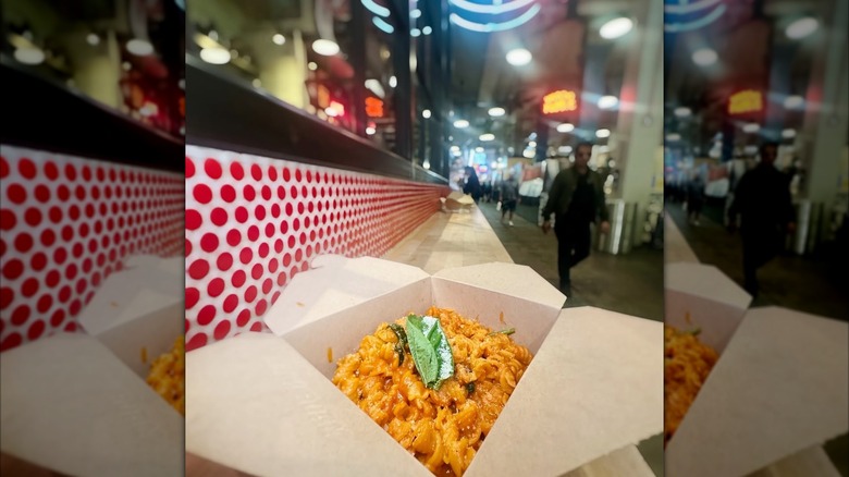 pasta in a cardboard takeout container outside of a restaurant