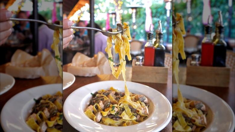 Person lifting a forkful of fettucine with fresh seafood and mushrooms