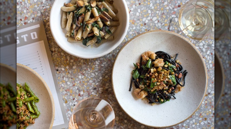A spread of Italian dishes and a glass of wine on a light-colored table