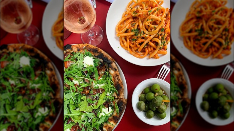 Pizza, pasta, olives, and wine on a red table