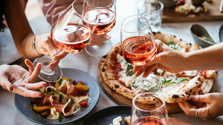 Close-up of friends toasting with pink wine over an Italian dinner