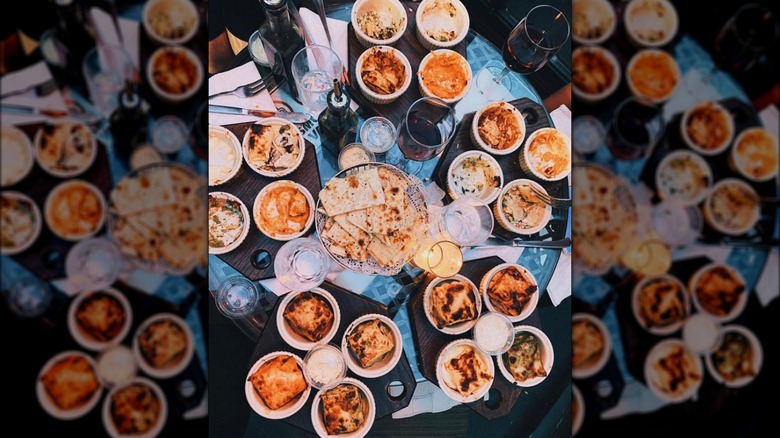A huge spread of different lasagnas on a table with a dark tablecloth