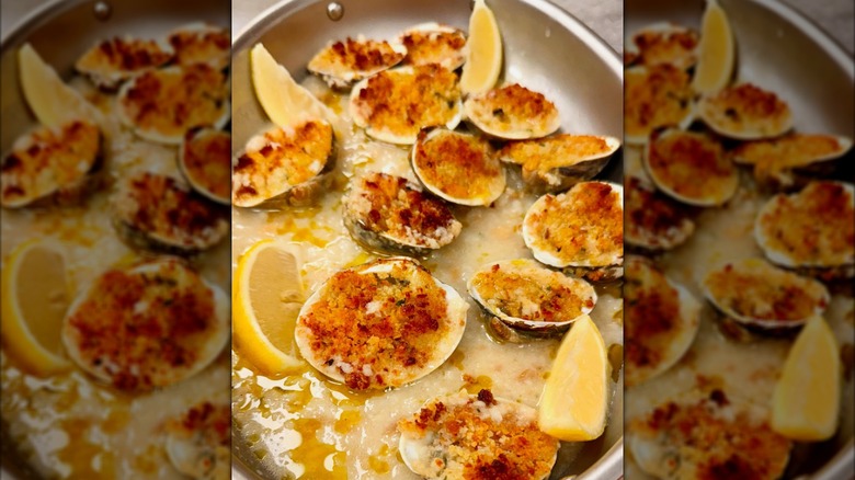A close-up of baked clams on ice with lemon
