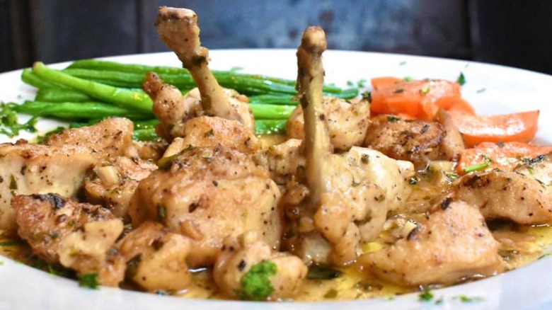 A close-up of a chicken dish with vegetables on the side and sauce