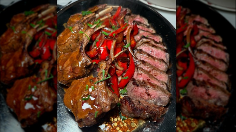 A close-up of sliced steaks in sauce with peppers in a black dish