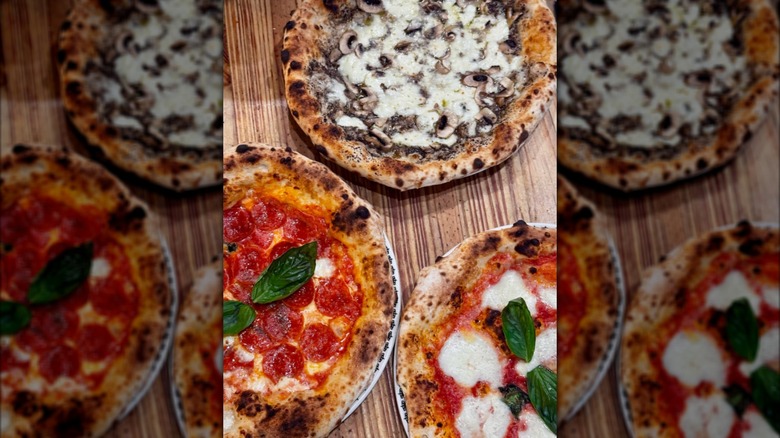 Three different Neapolitan pizzas on a wood table